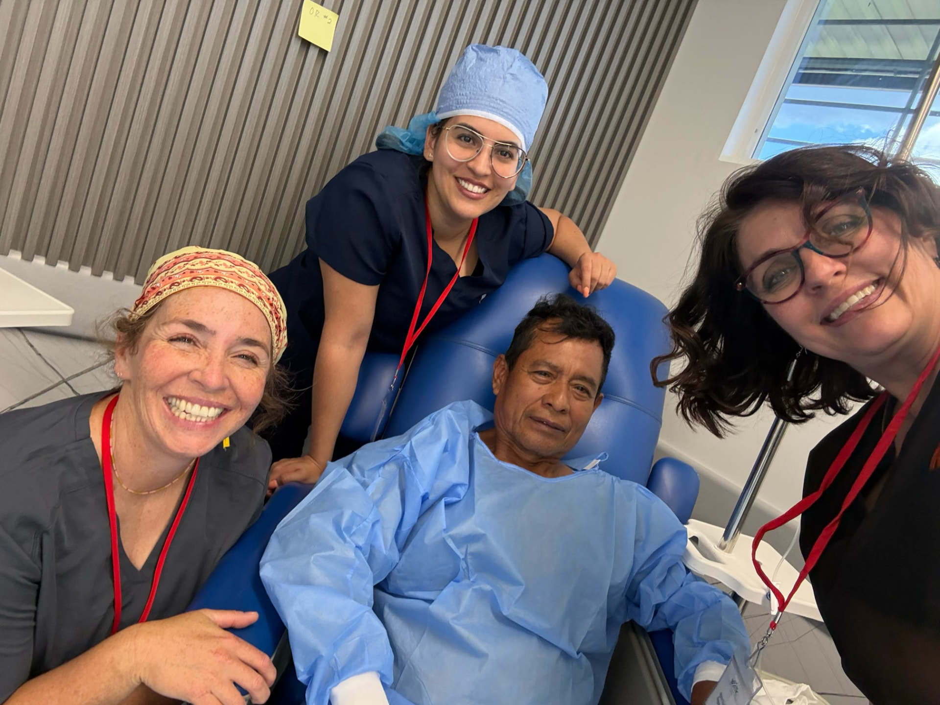 Volunteer nurses posing with a smiling patient before surgery
